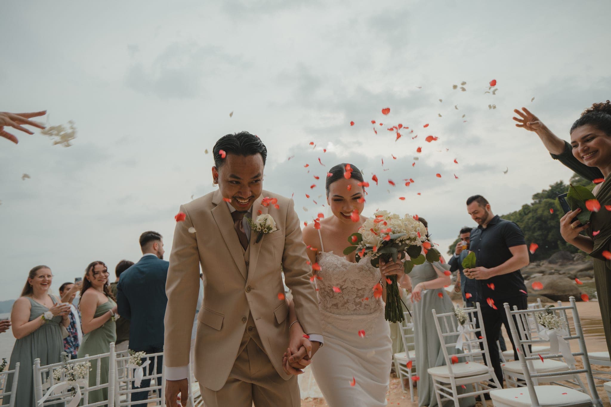 The couple laughing as rose petals fall around them