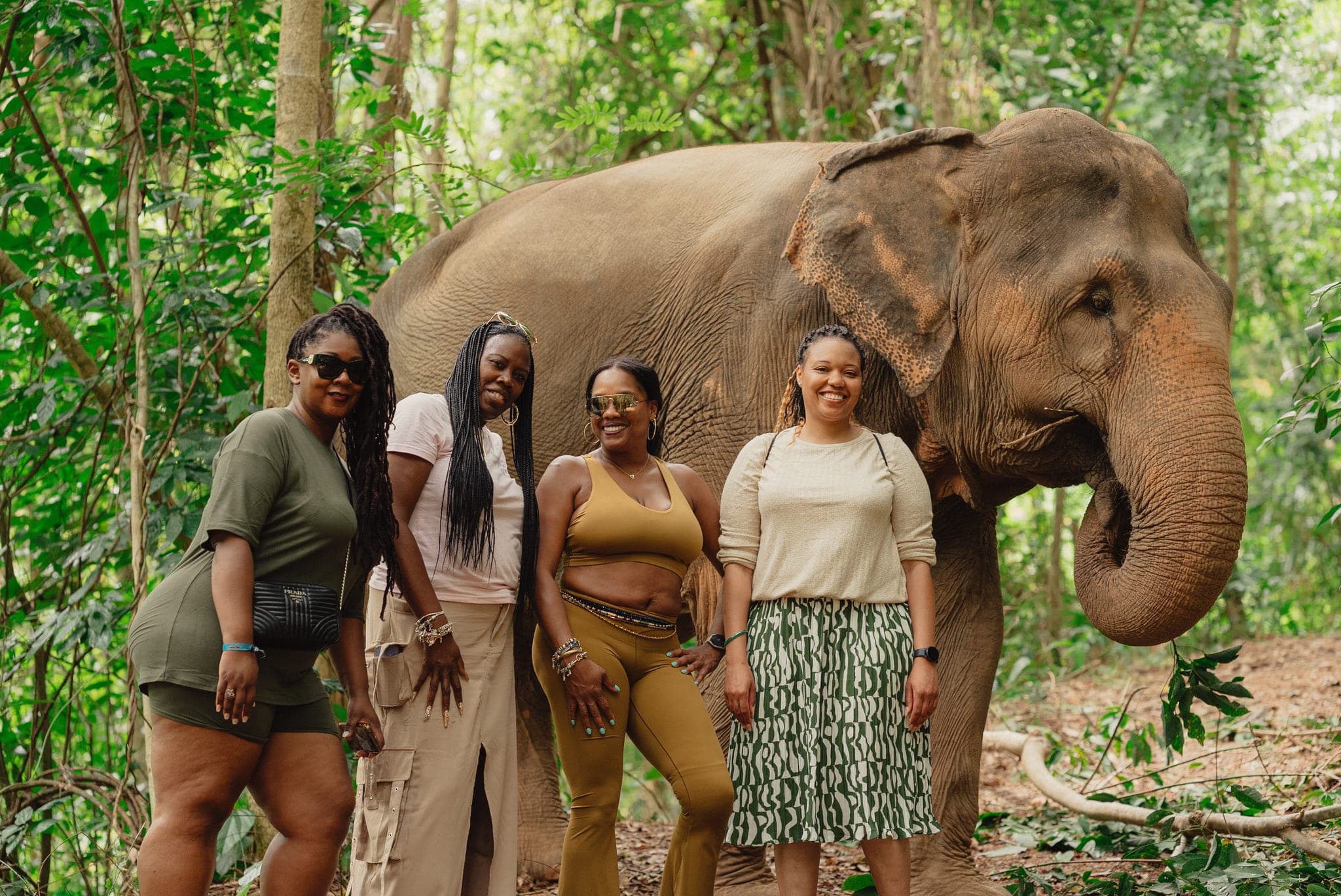 Four friends smiling beside the elephant
