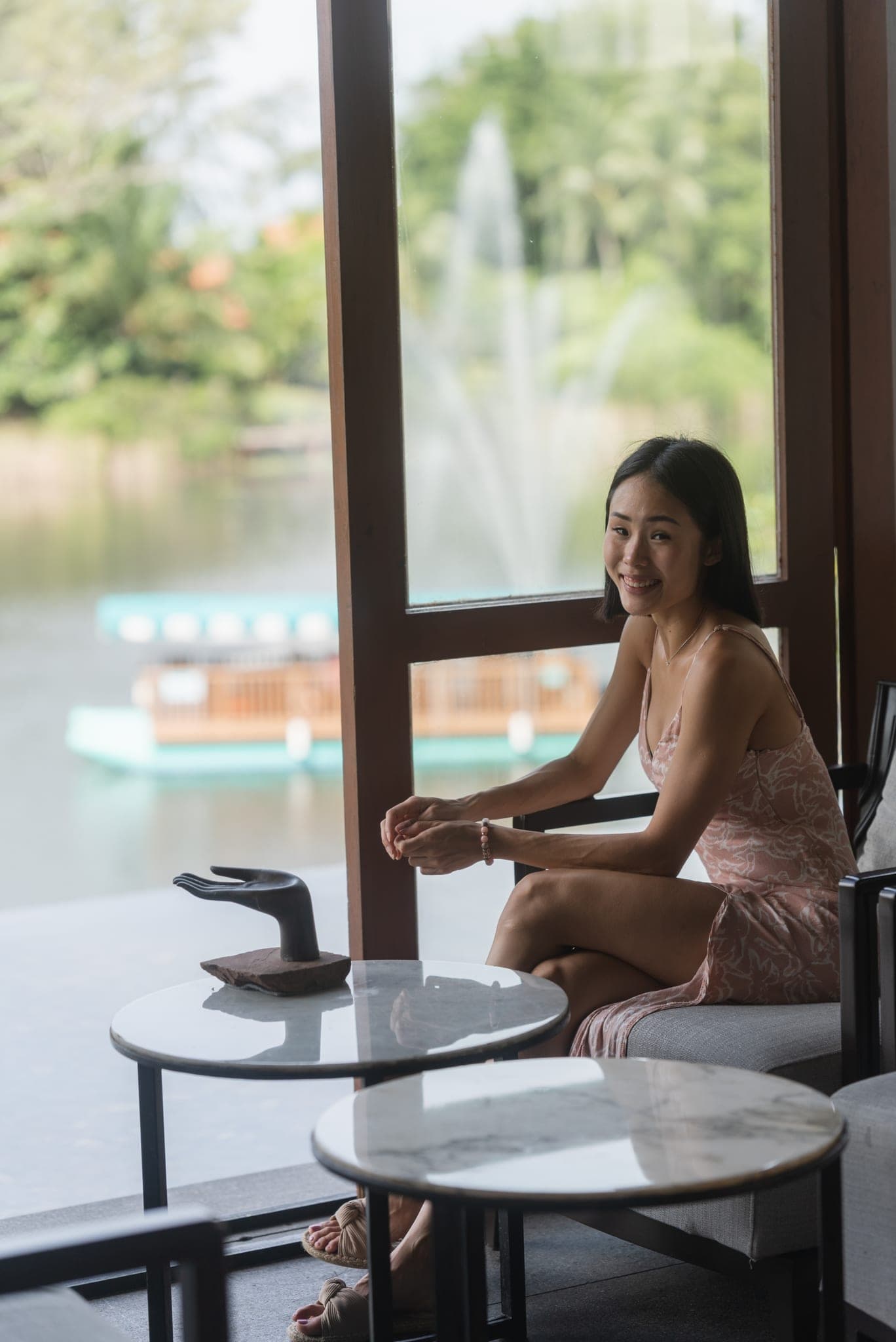 Smiling by the window, a boat on the lake behind