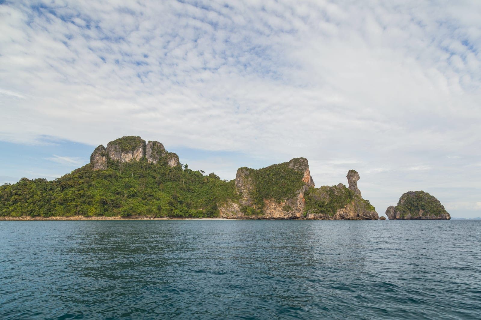 Ko Kai seen from a boat, its rock shaped like a chicken's head and neck at the right end, calm sea in front