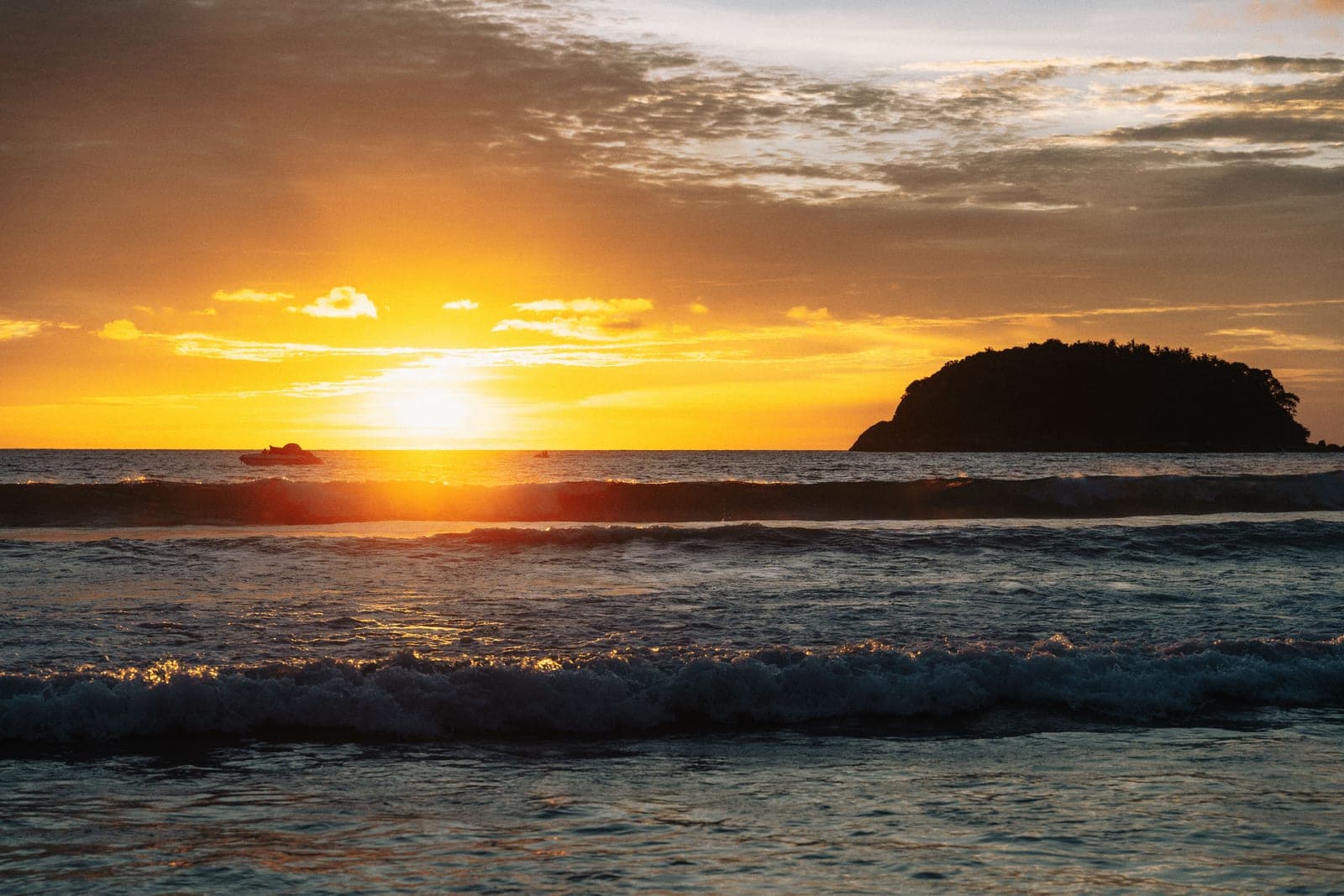 The sun going down over the sea beside the island of Ko Pu, waves breaking in front