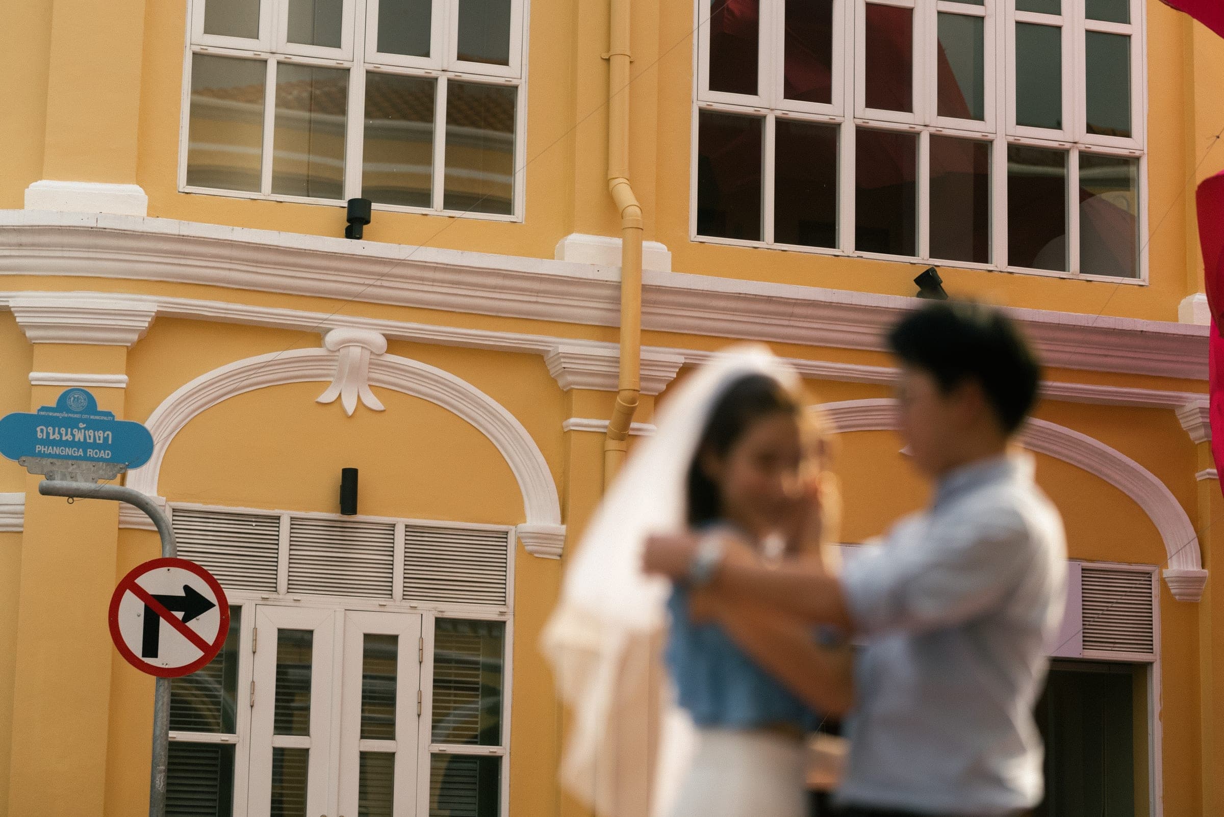 Couple mid-spin in front of a butter-yellow Sino-Portuguese shophouse, softly blurred with movement