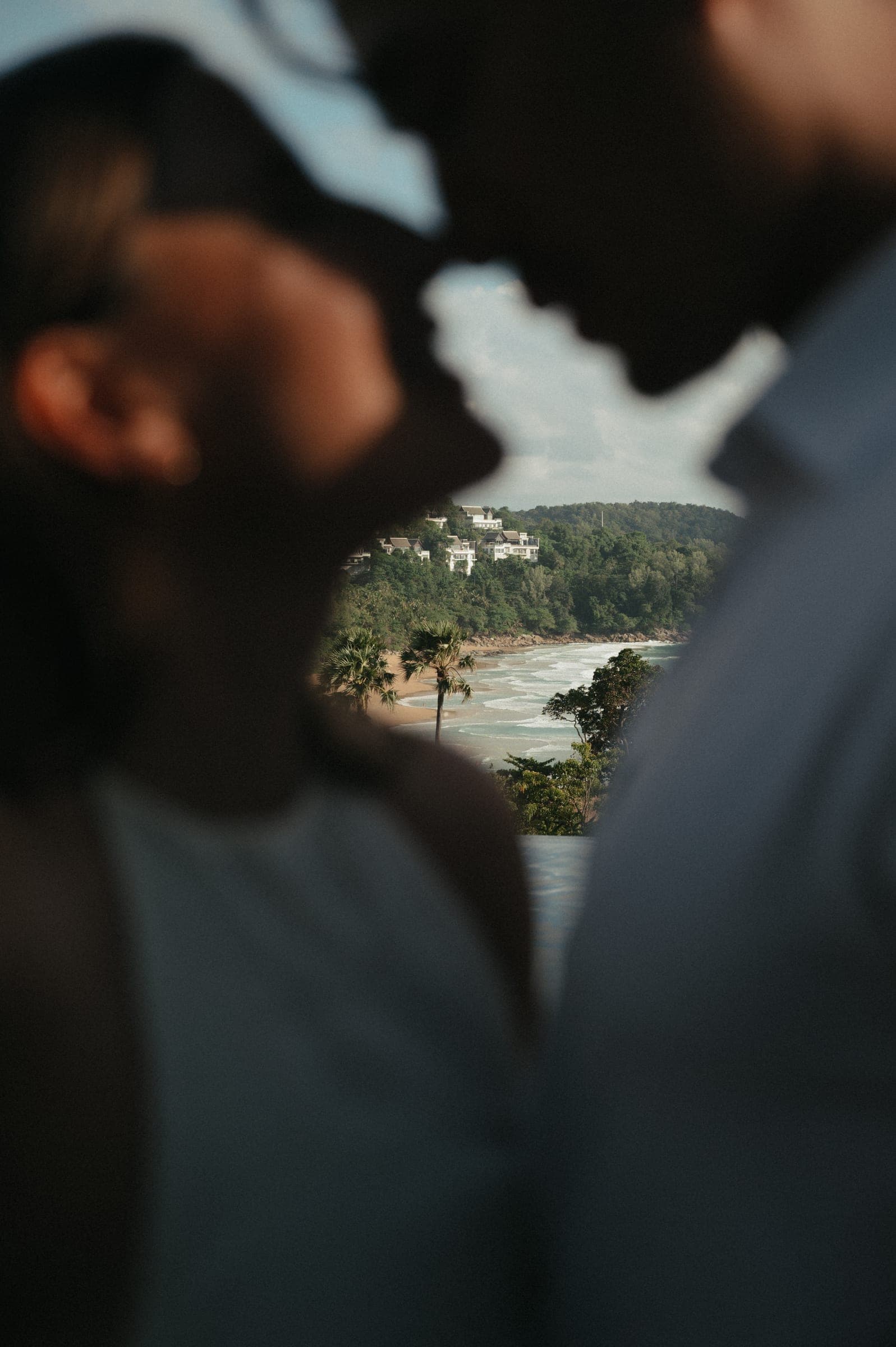 Close profile of a couple, the beach and headland softly out of focus far below